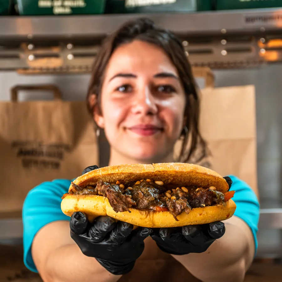 Miembro del equipo de Estafetén mostrando un mollete de carne mechada recién montado